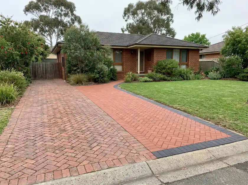 Older red clay paver driveway widened with a new strip of matching herringbone pavers and a charcoal border at a Canberra brick home