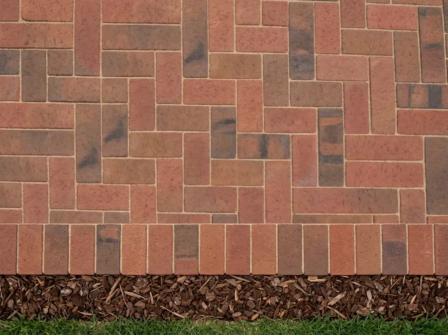 Top view of the same red-brown clay pavers laid in 90 degree herringbone against a border row