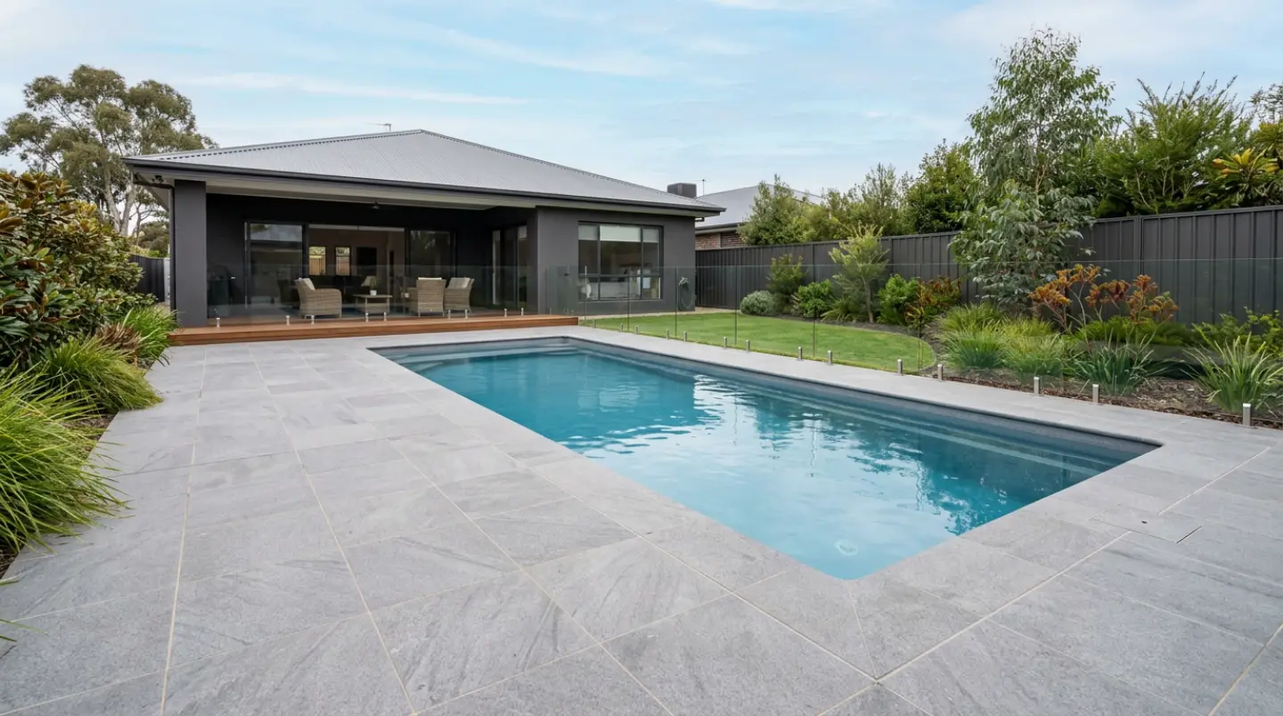 Grey stone-look porcelain pool surround with matching coping around a rectangular pool at a Canberra home