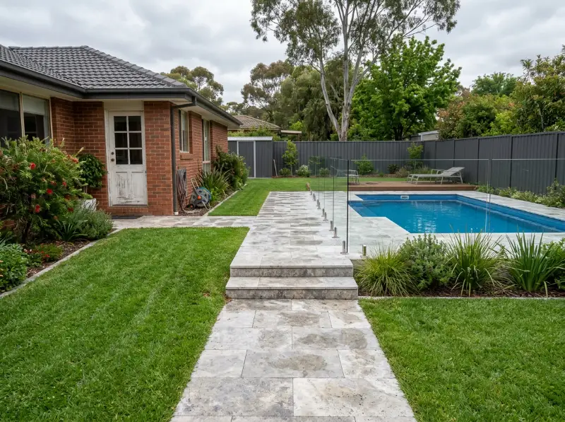 Silver travertine path with two wide steps leading from the back door to a glass pool fence