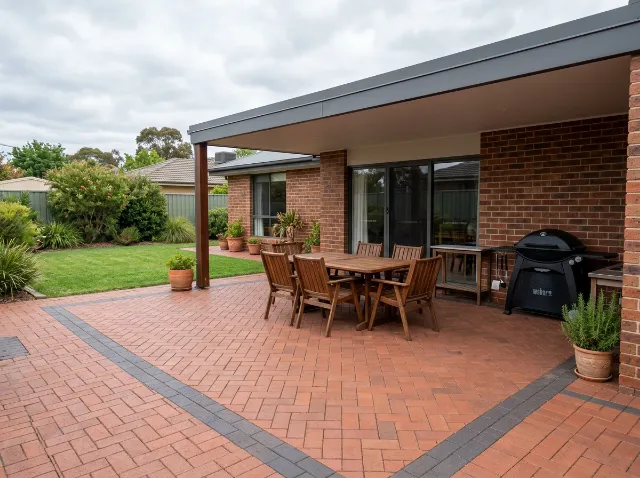 Red clay paver entertaining area in herringbone with a charcoal border under an alfresco roof