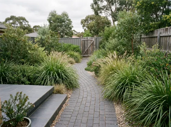 Charcoal clay paver garden path leading from tiled steps through native grasses to a side gate